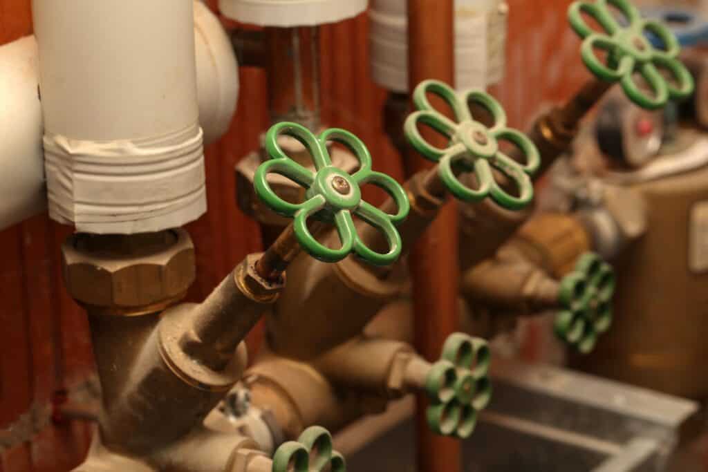 VVS-installation med grønne ventilhåndtag på varmerør i fyrrum